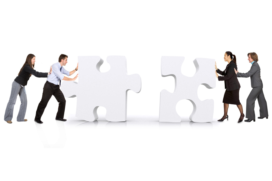 Image: People pushing two large puzzle pieces towards each other Image: People pushing two large puzzle pieces towards each other