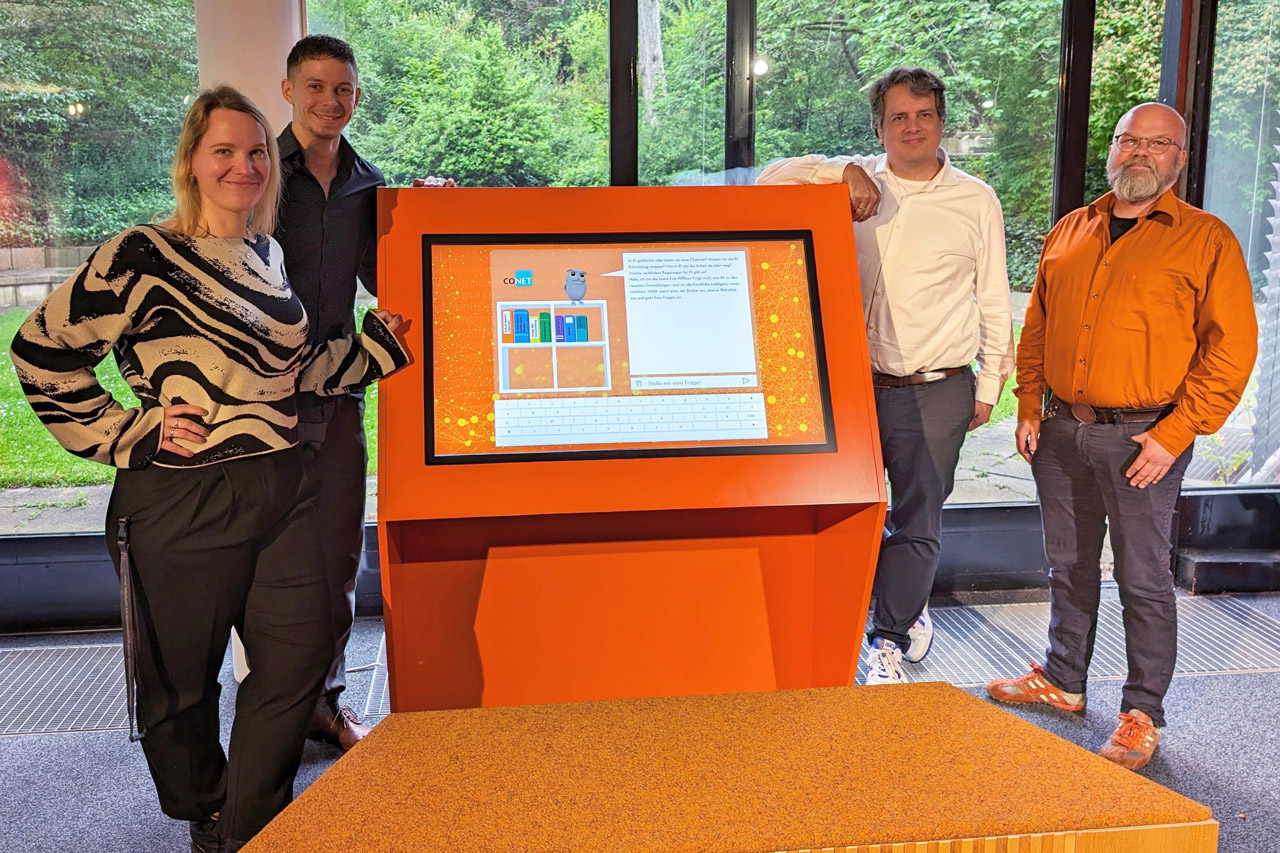Foto: Gruppenfoto vor dem Exponat GenAI Eule Piffikus