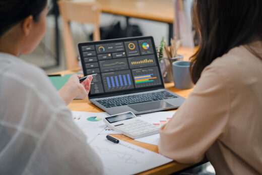 Foto: Digitalisierung im Finanzsektor - Frauen sitzen vor Notebook mit Finanzdiagrammen