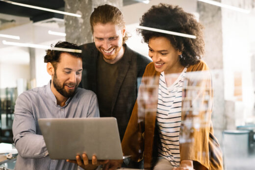 Foto: Tipps und Tricks für Microsoft Teams - Gruppe Menschen schaut gemeinsam auf Notebook