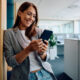 Foto: Frau haelt im Buero Smartphone in der Hand