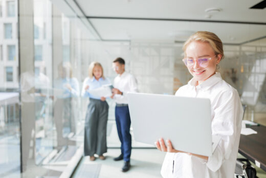 Foto: Frau in Büroumgebung hält Laptop in der Hand