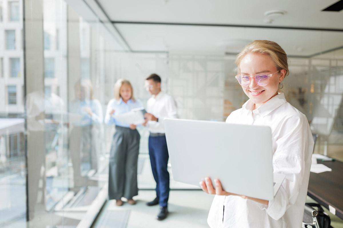 Foto: Frau in Büroumgebung hält Laptop in der Hand