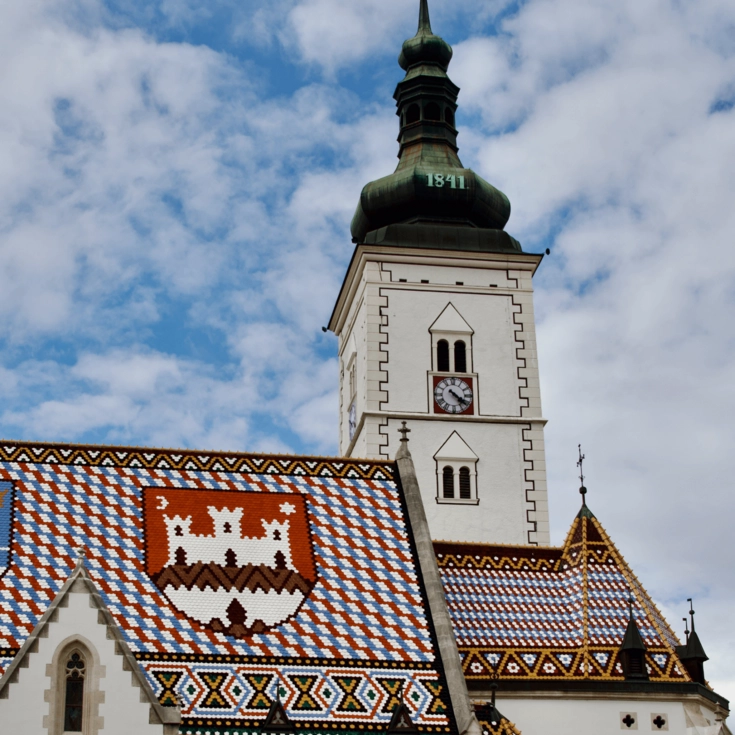 Blick auf die St.-Markus-Kirche in Zagreb mit dem farbig gekachelten Dach und dem Uhrturm.