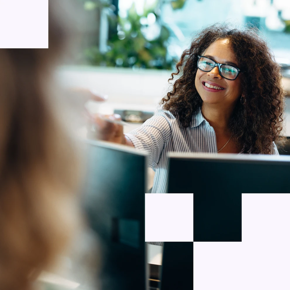 Frau arbeitet lächelnd an einem Laptop in einer modernen Büroumgebung