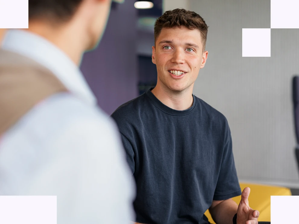Werkstudent in dunklem T-Shirt unterhält sich offen mit einem IT-Consultant