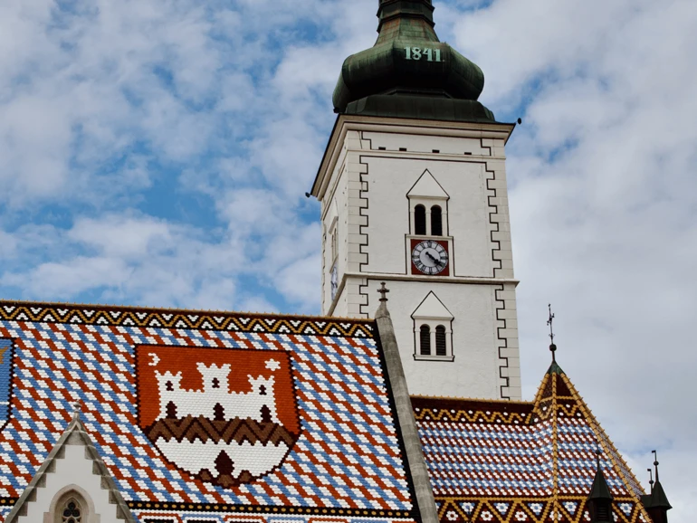 Markuskirche mit ihrem farbenfrohen, gemusterten Ziegeldach und dem markanten Uhrturm.