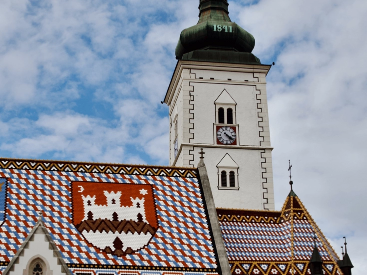 Markuskirche mit ihrem farbenfrohen, gemusterten Ziegeldach und dem markanten Uhrturm.