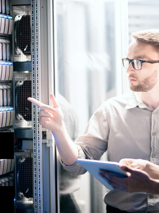 Foto: Zwei Männer stehen mit Tablet vor einem Server