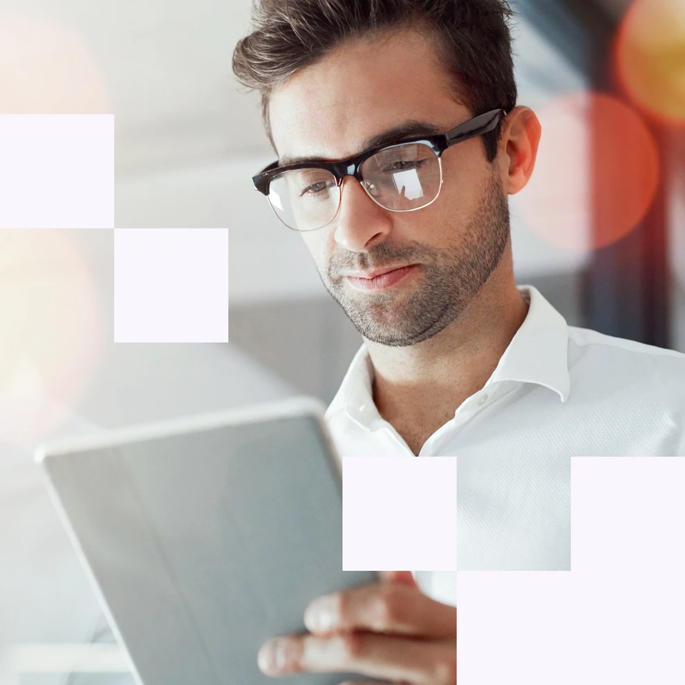 Mann mit schwarzer Brille im weißen Hemd arbeitet konzentriert an einem Tablet