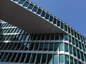 Moderne Frankfurter Bürogebäude mit überbrückender Glasfassade gegen den blauen Himmel.