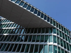 Moderne Frankfurter Bürogebäude mit überbrückender Glasfassade gegen den blauen Himmel.
