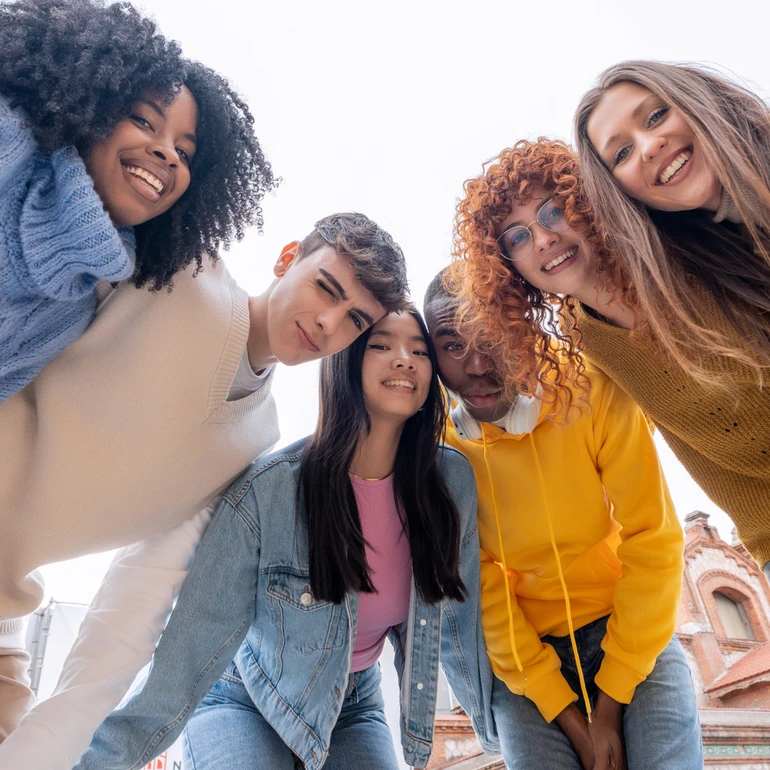 Gruppe junger Erwachsener Gruppe von fünf jungen Menschen diverser Nationalität in bunter Freizeitkleidung schaut lächelnd von oben in die Kamera