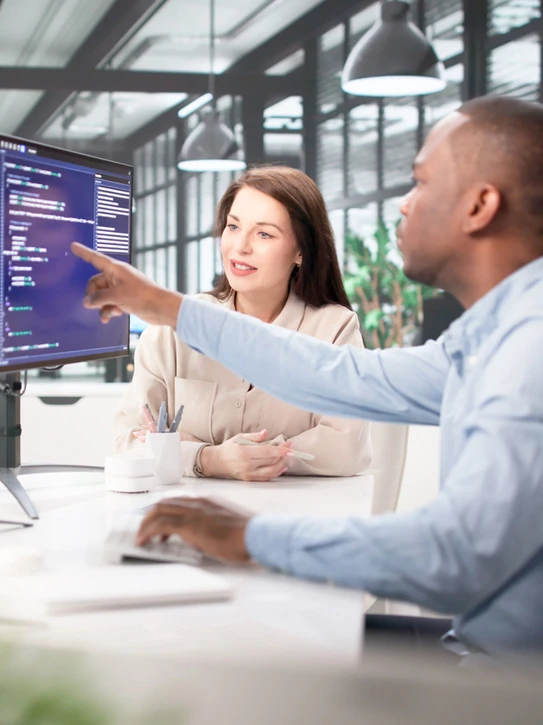 Foto: Kollege zeigt einer Kollegin Code auf einem Monitor