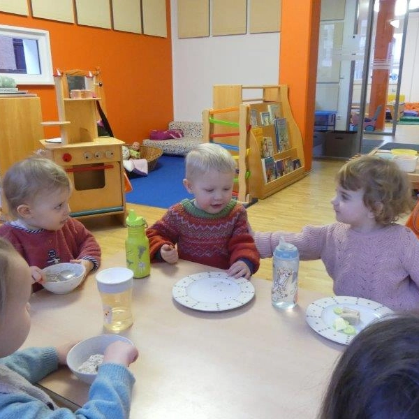 Kleinkinder frühstücken gemeinsam an einem Tisch in der Kita
