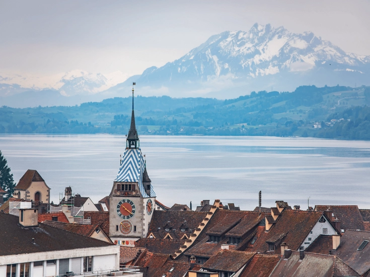 Blick über die Dächer von Baar zum Zugersee und den schneebedeckten Alpen.