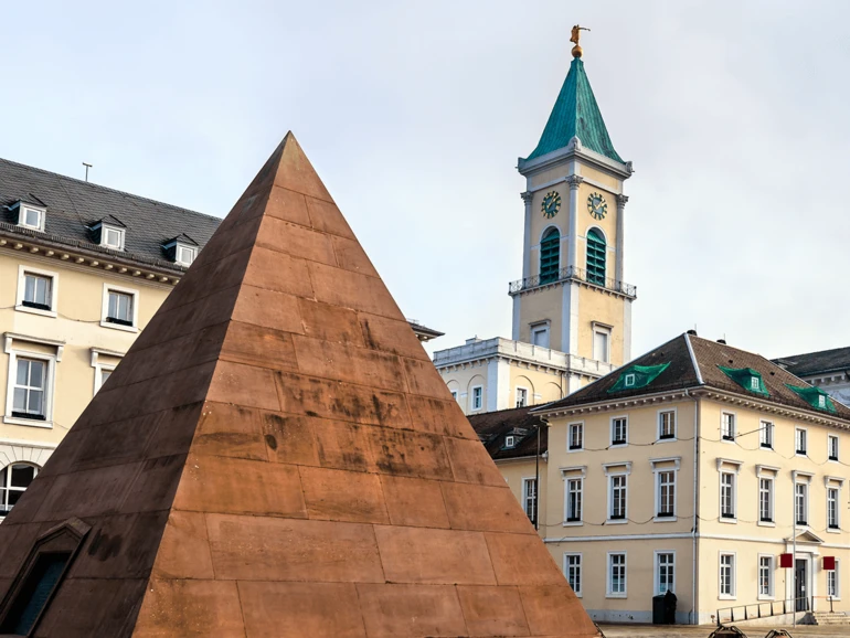 Sandsteinerne Pyramide auf dem Karlsruher Marktplatz vor der Stadtkirche und umliegenden Gebäuden.