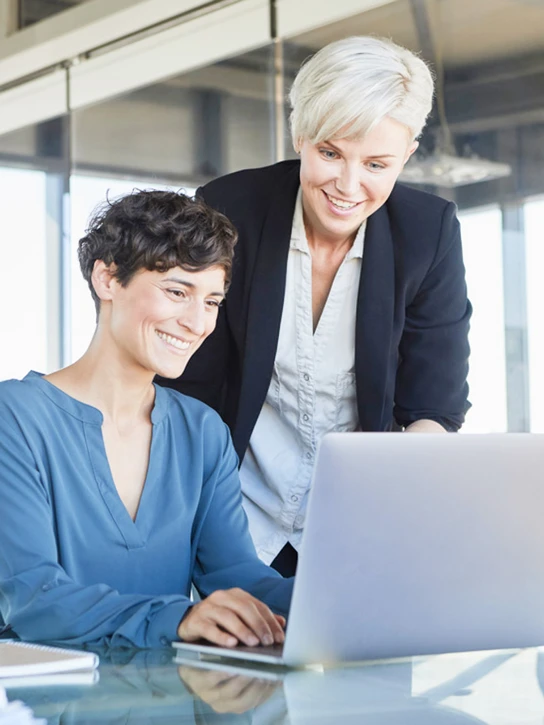 Foto: Zwei Kolleginnen schauen gemeinsam auf ein Notebook