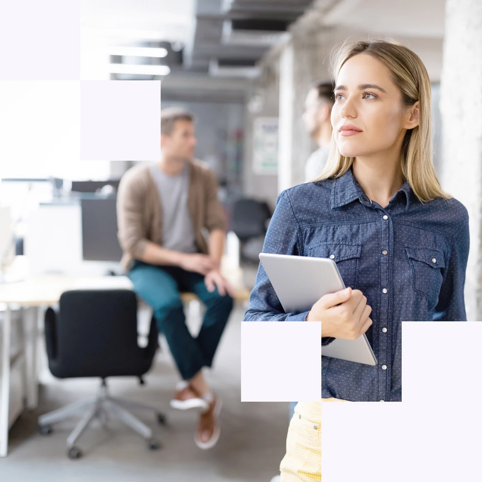 Foto: Frau hält Tablet in der Hand, Arbeitskollegen im Hintergrund unterhalten sich.