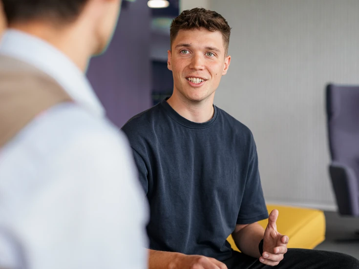 Werkstudent mit dunklem T-Shirt im Gespräch