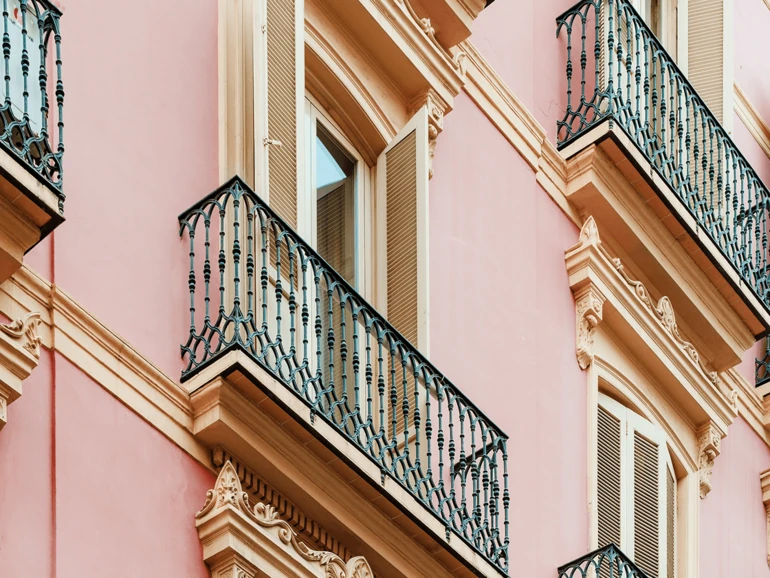 Fassade eines historischen Gebäudes in warmen Farben mit verzierten Eisenbalkonen.
