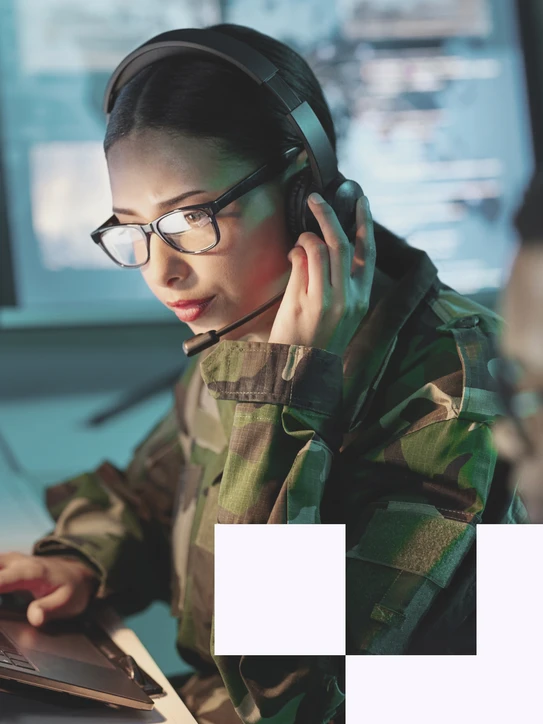 Frau arbeitet in Uniform an Laptop in sicherheitskritischer Umgebung – Symbol für digitale Verteidigung