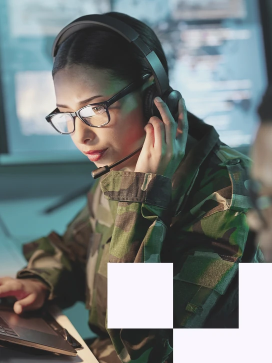 Frau arbeitet in Uniform an Laptop in sicherheitskritischer Umgebung – Symbol für digitale Verteidigung