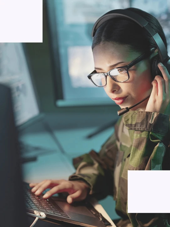 Frau arbeitet in Uniform an Laptop in sicherheitskritischer Umgebung – Symbol für digitale Verteidigung