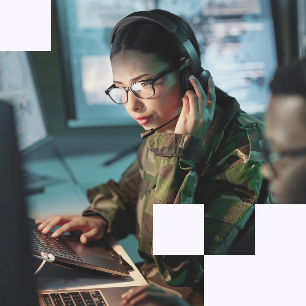 Frau arbeitet in Uniform an Laptop in sicherheitskritischer Umgebung – Symbol für digitale Verteidigung