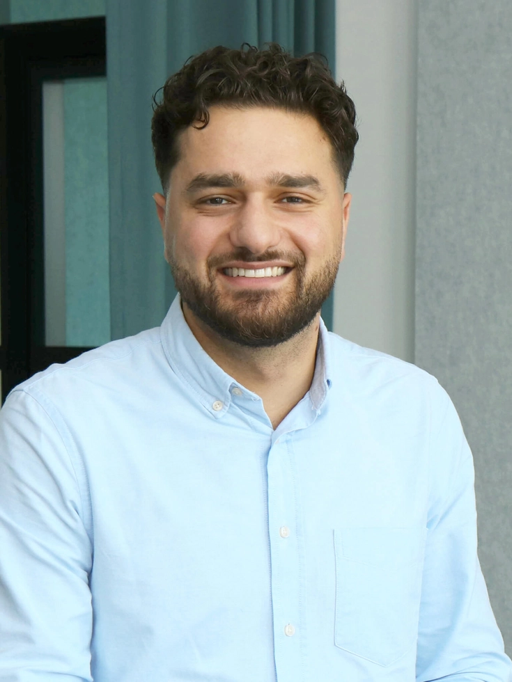 Porträt eines lächelnden jungen Mannes in hellblauem Hemd in einem modernen Büro