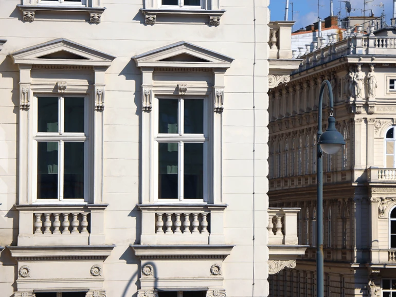 Detailaufnahme klassizistischer Gebäudefassaden mit Säulen, Gesimsen und dekorativen Elementen.