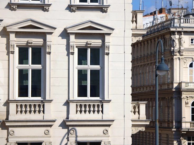 Detailaufnahme klassizistischer Gebäudefassaden mit Säulen, Gesimsen und dekorativen Elementen.