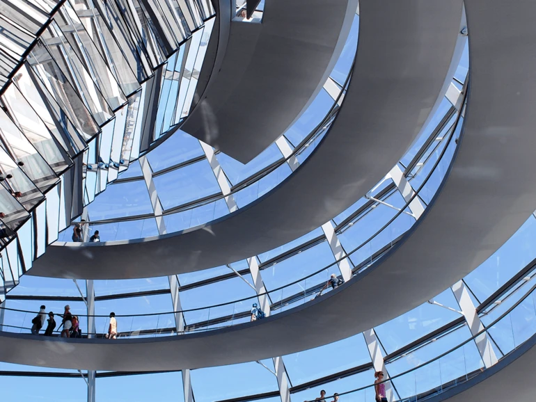 Innenansicht der gläsernen Spiralkonstruktion der Reichstagskuppel in Berlin mit Besuchern auf den Rundwegen.