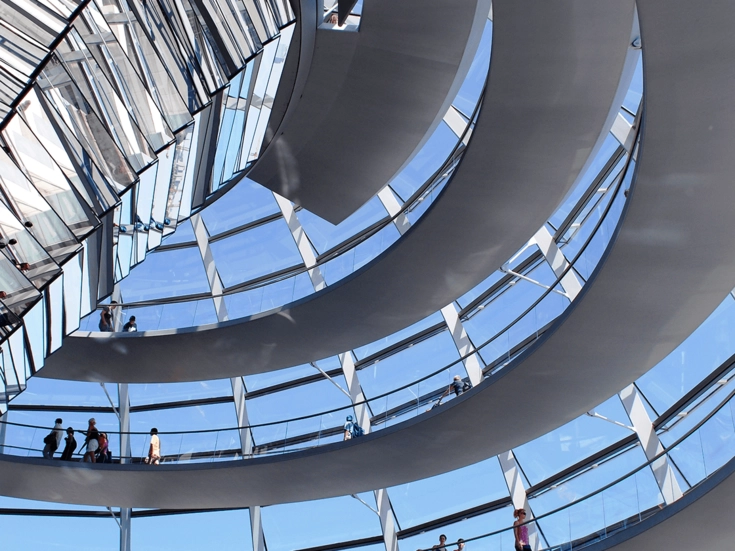 Innenansicht der gläsernen Spiralkonstruktion der Reichstagskuppel in Berlin mit Besuchern auf den Rundwegen.