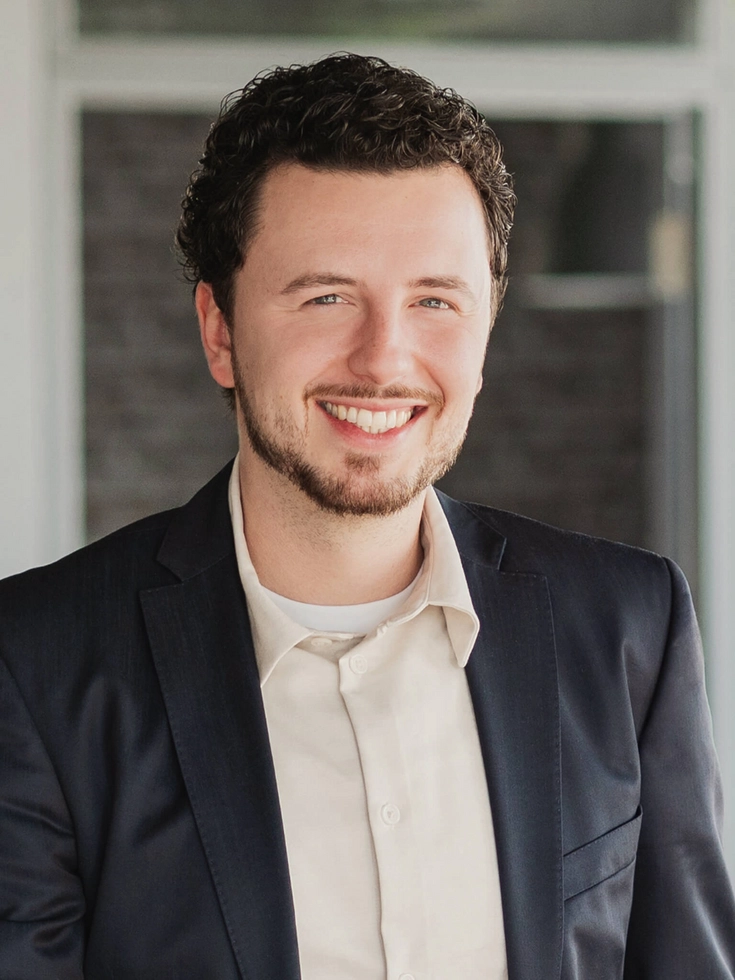 Porträt eines lächelnden CONET Mitarbeiters im Business-Outfit in moderner Büroatmosphäre