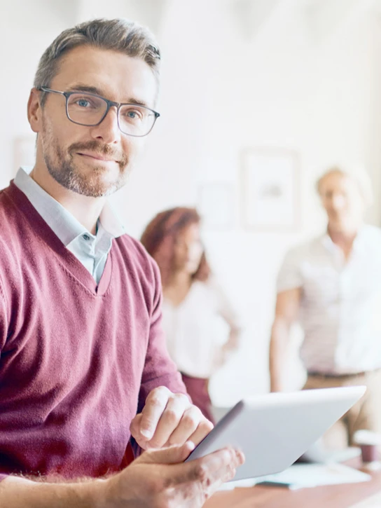 Foto: Mann mit Tablet in der Hand schaut in die Kamera